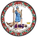 A circular seal with the words "Virginia" on the top and "Sic Semper Tyrannis" on the bottom. In the center, a woman wearing a blue toga and Athenian helmet stands on the chest of dead man wearing a purple breastplate and skirt. The woman holds a spear and sheathed sword. The man holds a broken chain while his crown lies away from the figures. Orange leaves encircle the seal.