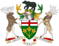 A central shield with the upper part showing the red cross of St. George and the lower part showing three golden maple leaves on a green background. There is a black bear on top of a knight's helmet above the shield with a moose to the left and a Canadian deer to the right. The province's motto "Ut incepit Fidelis sic permanet", Latin for "Loyal she began, loyal she remains" is written below the crest.