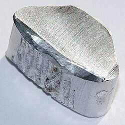 An oblong piece of silvery metal on a glossy surface